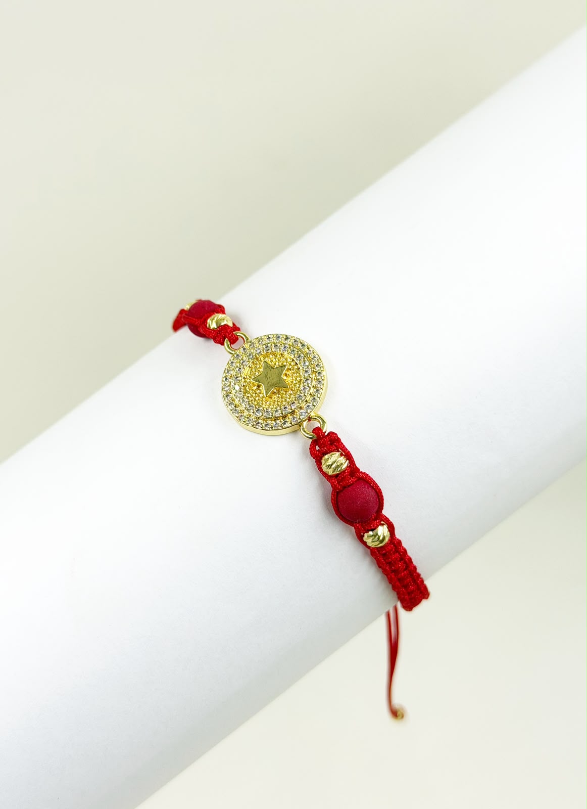 Pulsera artesanal con dije de medalla y estrella grabada, decorada con detalles brillantes.