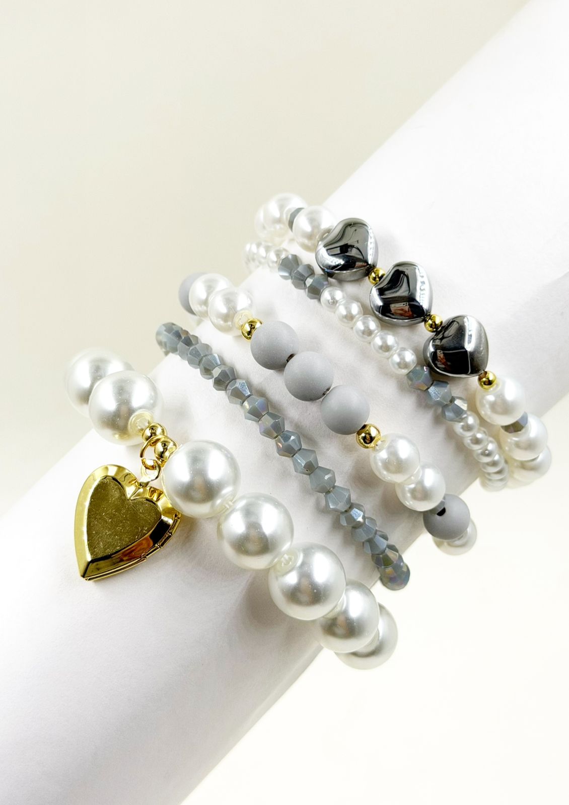 Pulsera femenina con cuentas decorativas de diferentes tamaños y dije de corazón sobre la muñeca.