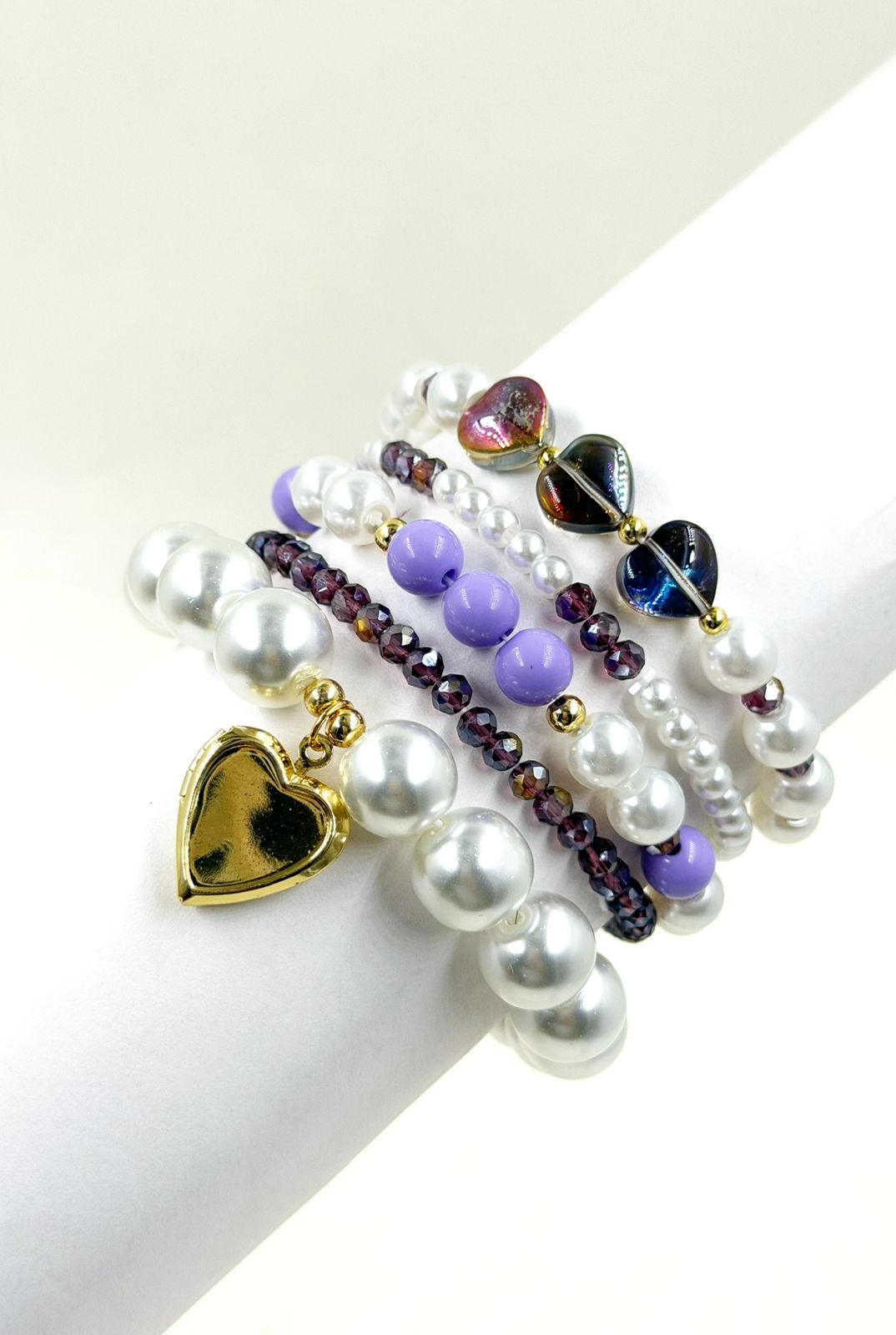 Pulsera femenina con cuentas decorativas de diferentes tamaños y dije de corazón sobre la muñeca.