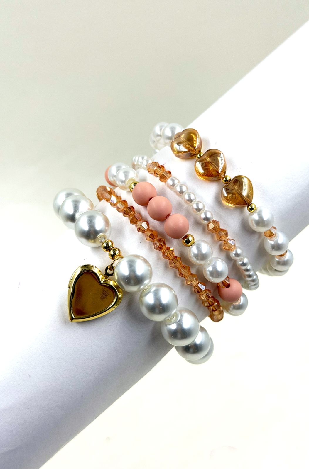 Pulsera femenina con cuentas decorativas de diferentes tamaños y dije de corazón sobre la muñeca.