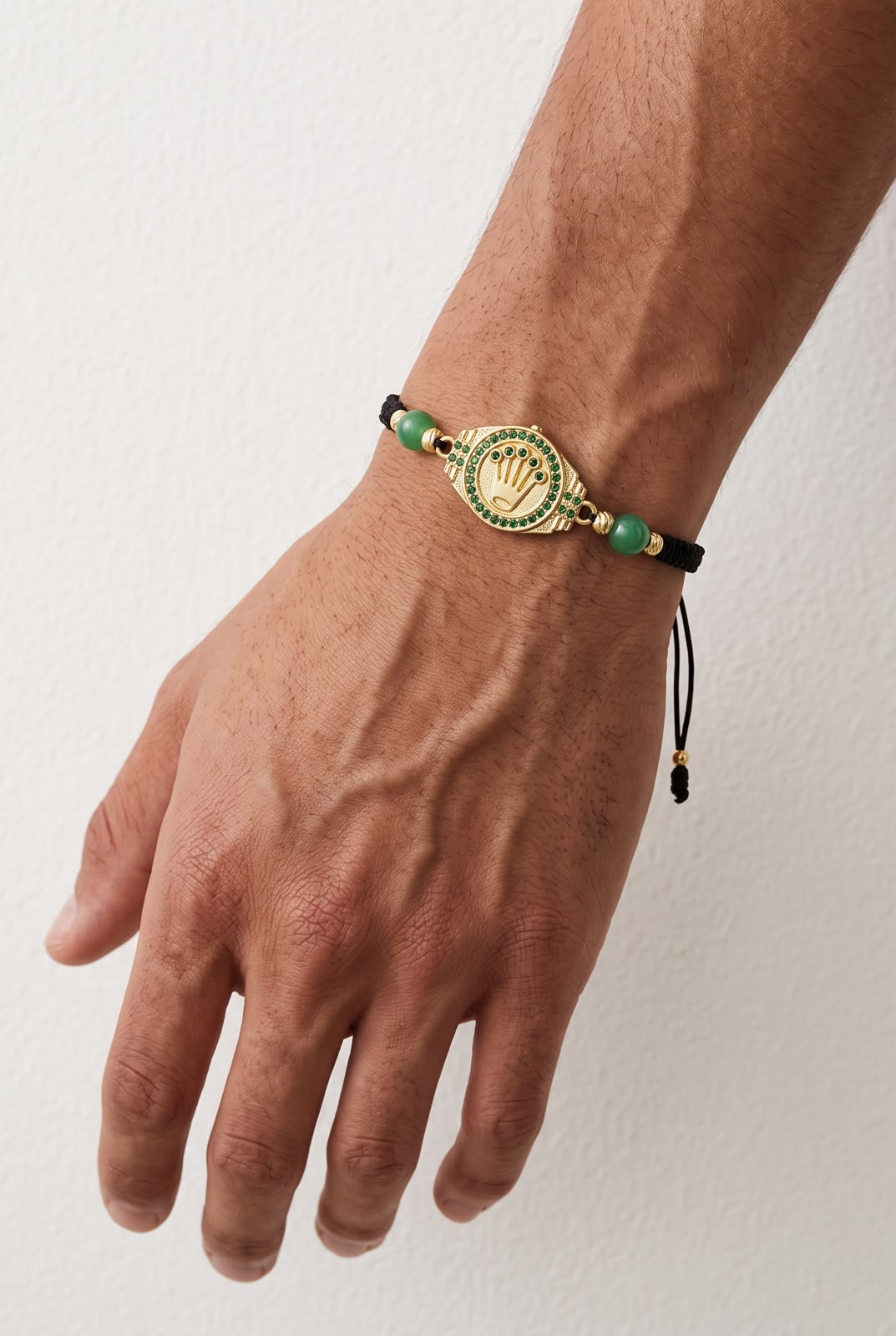 Pulsera artesanal con dije de corona sobre fondo dorado, de diseño delicado y elegante.