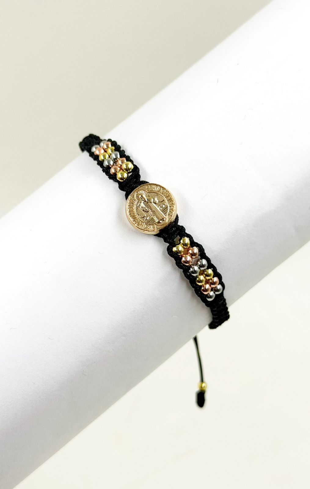 Pulsera artesanal con dije de San Benito y diseño delicado de estilo simbólico.