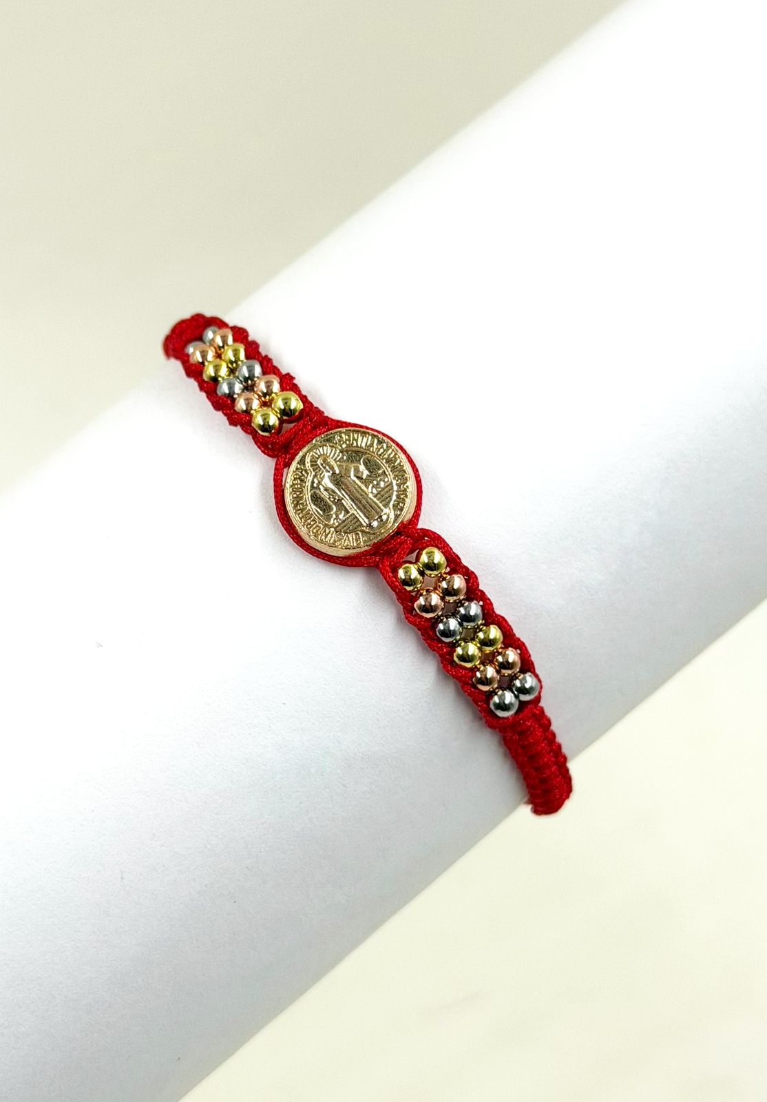 Pulsera artesanal con dije de San Benito y diseño delicado de estilo simbólico.