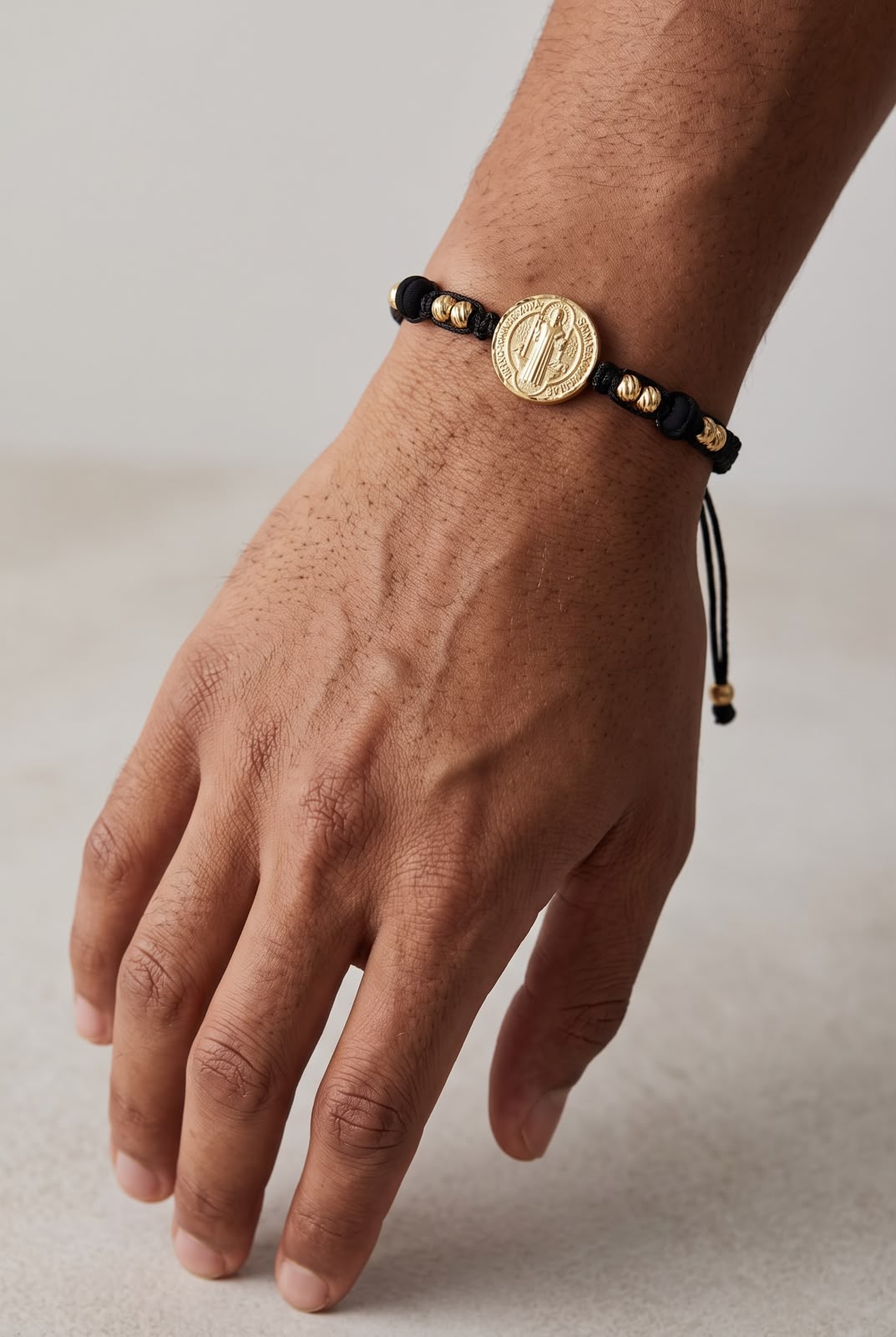 Pulsera artesanal sencilla con dije de San Benito y diseño minimalista.