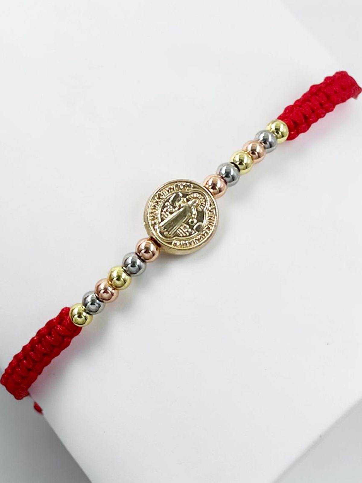 Pulsera artesanal con dije de San Benito, de diseño delicado y elegante.