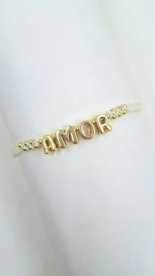 "Pulsera Amor Perlado en macramé beige con balines rodinados, perla esmaltada y frase Amor dorada